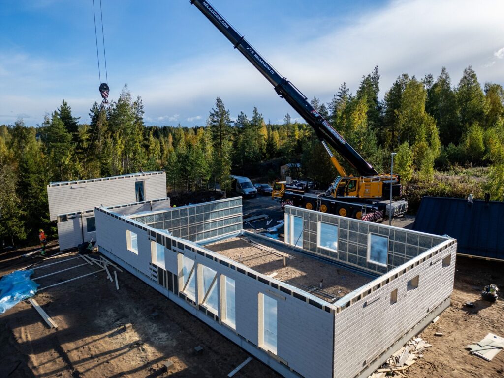 Ulkoa valmis talopaketti työmaalla, seinät pystyssä ennen vesikattoa